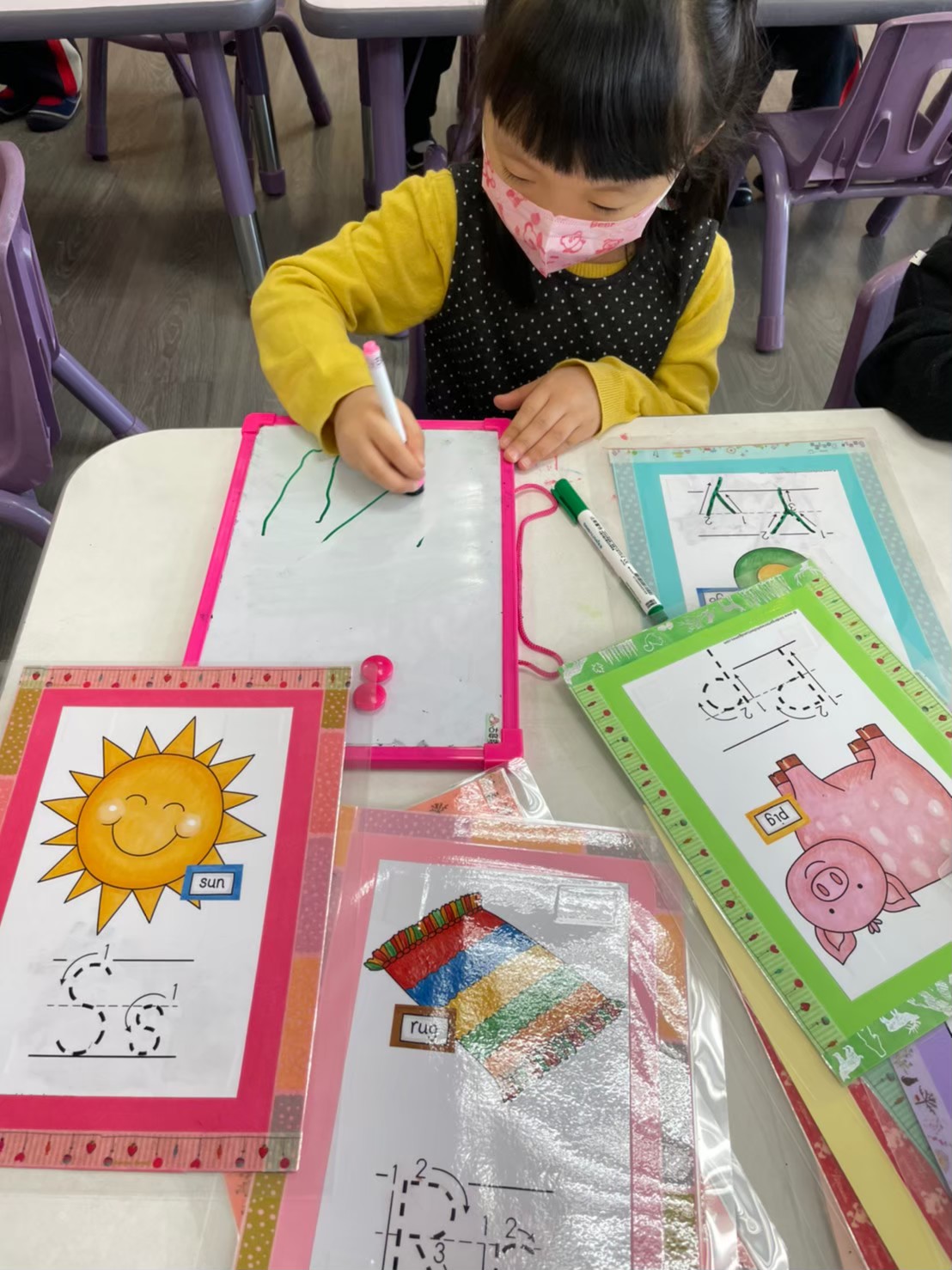 A child practicing letter writing with colorful flashcards